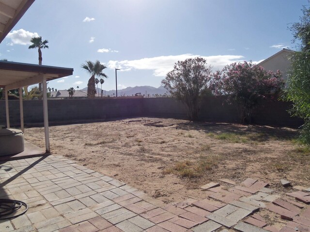 view of yard featuring a patio area, a fenced backyard, and a mountain view