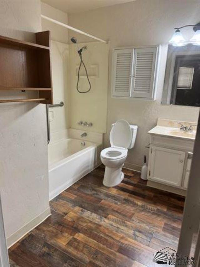 bathroom with baseboards, toilet, wood finished floors, vanity, and shower / bathing tub combination