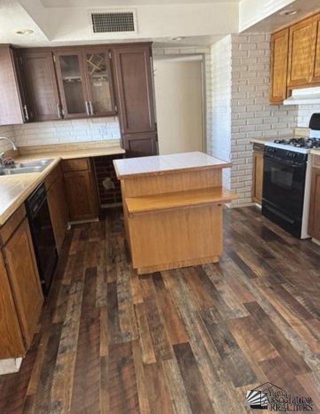 kitchen featuring black appliances, dark wood-style flooring, a sink, and visible vents