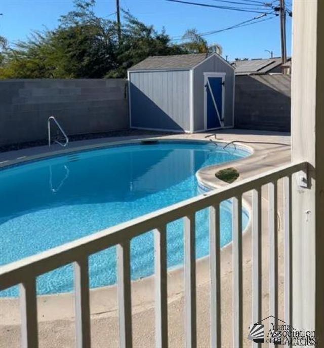 view of pool featuring an outbuilding, a storage unit, fence private yard, and a fenced in pool