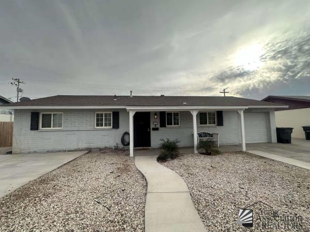 ranch-style house with a garage, covered porch, driveway, and fence