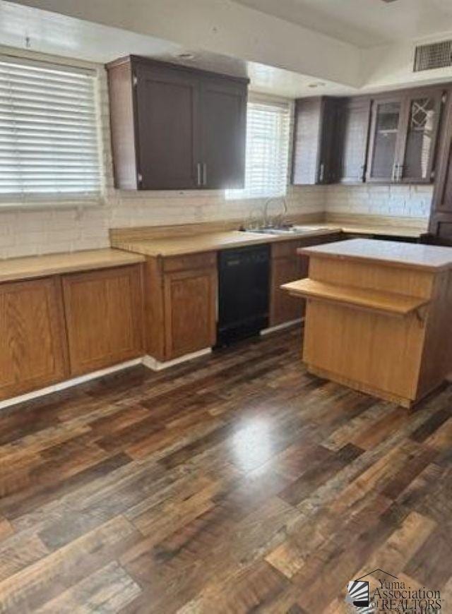 kitchen featuring a sink, dark wood finished floors, dishwasher, and light countertops