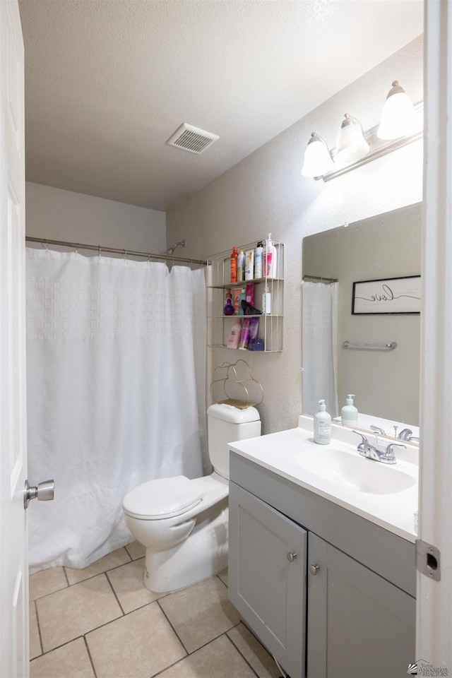 bathroom featuring walk in shower, toilet, a textured ceiling, vanity, and tile patterned flooring