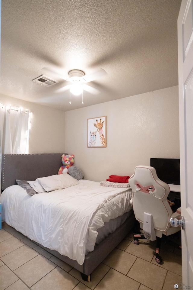 tiled bedroom with a textured ceiling and ceiling fan