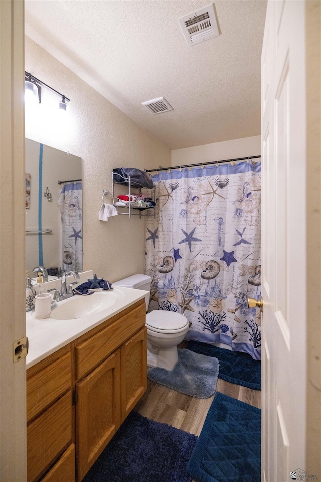 bathroom featuring toilet, a textured ceiling, vanity, curtained shower, and hardwood / wood-style flooring