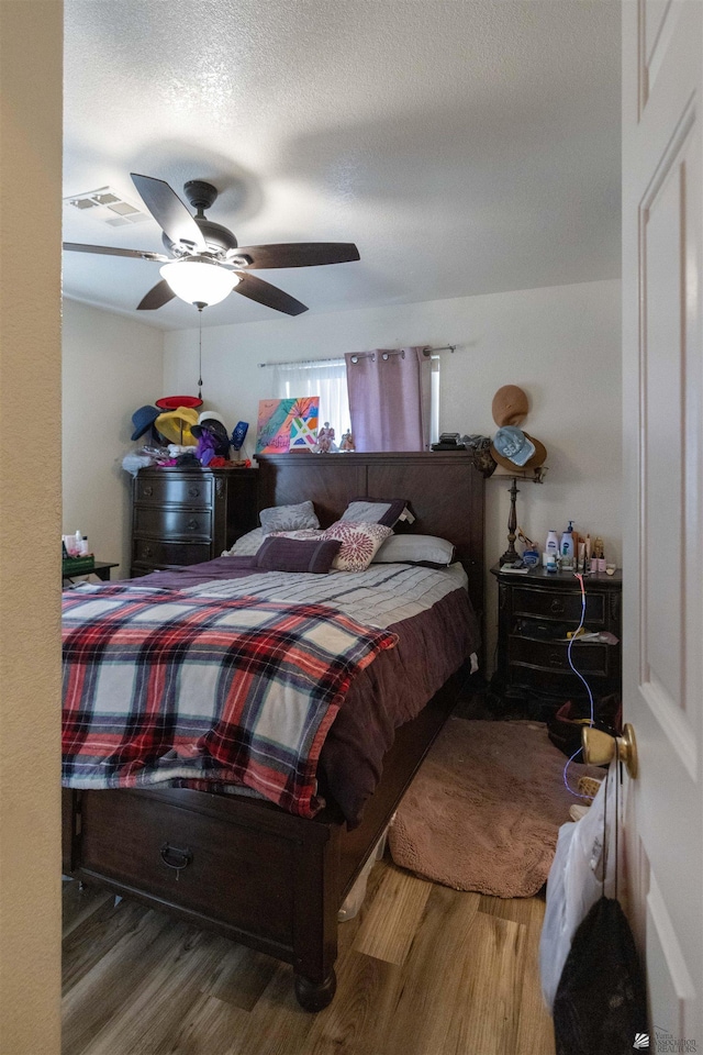 bedroom featuring ceiling fan, wood-type flooring, and a textured ceiling