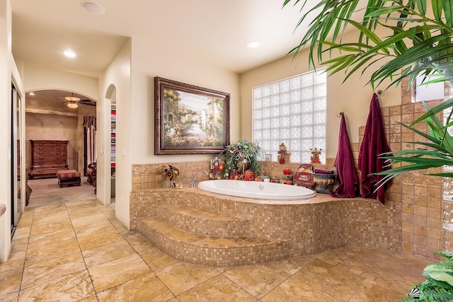 bathroom with ceiling fan and tiled tub