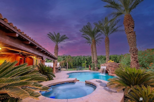 pool at dusk with an in ground hot tub