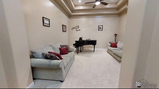 living room with a raised ceiling, ceiling fan, and carpet