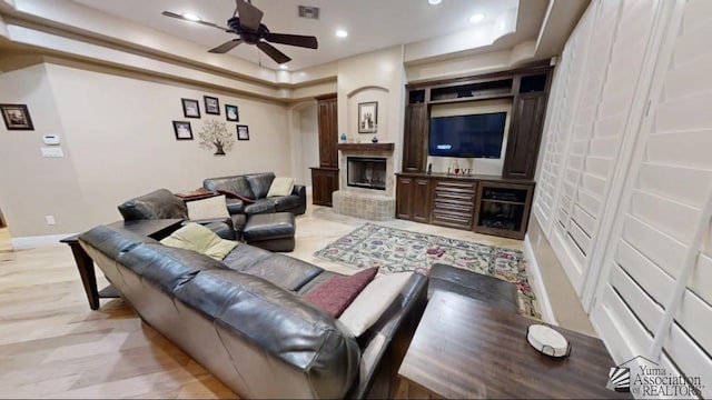 living room featuring a raised ceiling and ceiling fan