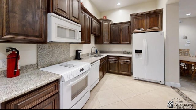 kitchen featuring decorative backsplash, dark brown cabinets, white appliances, sink, and light tile patterned floors