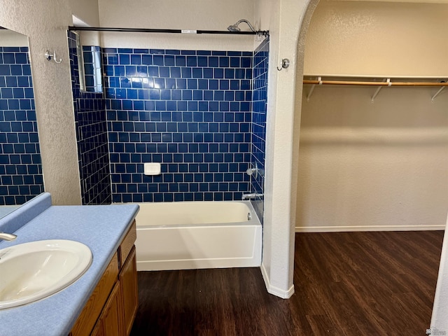 bathroom with hardwood / wood-style floors, vanity, and tiled shower / bath