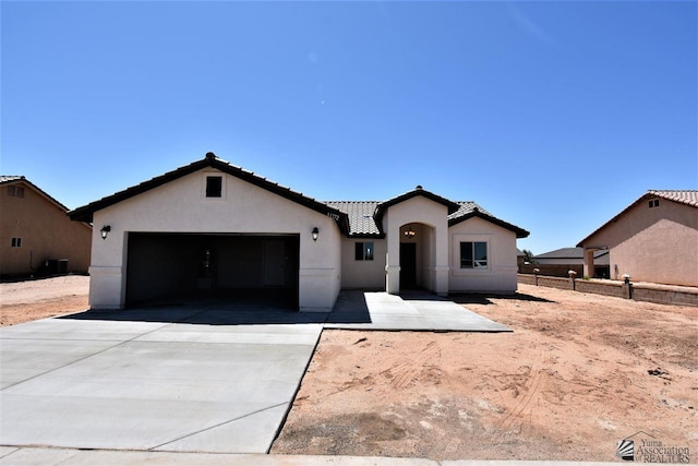 view of front facade with stucco siding, concrete driveway, fence, a garage, and a tiled roof