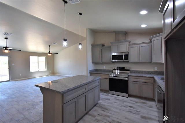 kitchen featuring visible vents, a center island, gray cabinets, vaulted ceiling, and stainless steel appliances