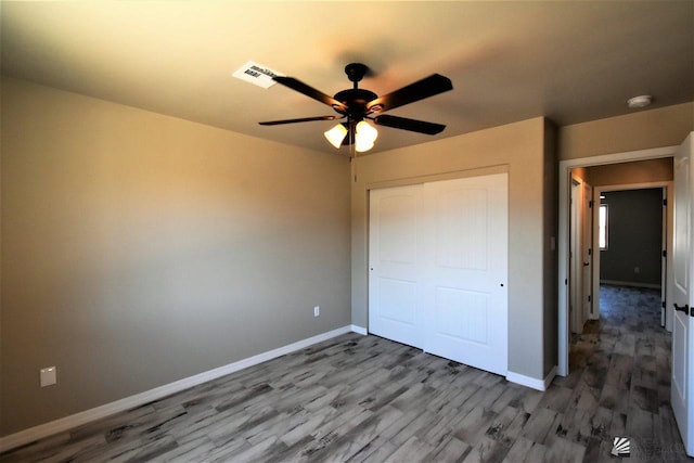 unfurnished bedroom featuring visible vents, baseboards, a ceiling fan, wood finished floors, and a closet