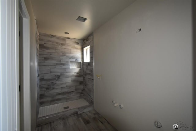 bathroom with tiled shower and wood finished floors