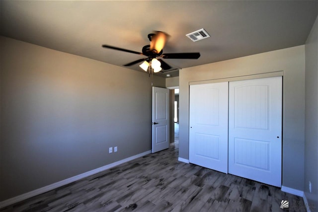 unfurnished bedroom featuring a closet, visible vents, baseboards, and wood finished floors