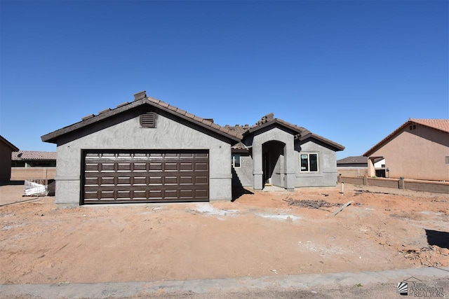 view of front of house with a tiled roof, fence, and stucco siding