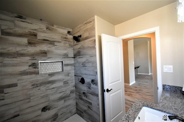 full bathroom with tiled shower and wood finished floors