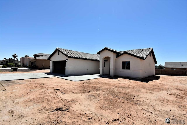 mediterranean / spanish-style house with driveway, a tile roof, an attached garage, fence, and stucco siding