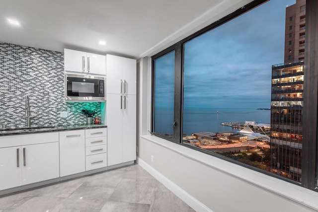 kitchen featuring white cabinets, tasteful backsplash, light tile floors, and sink