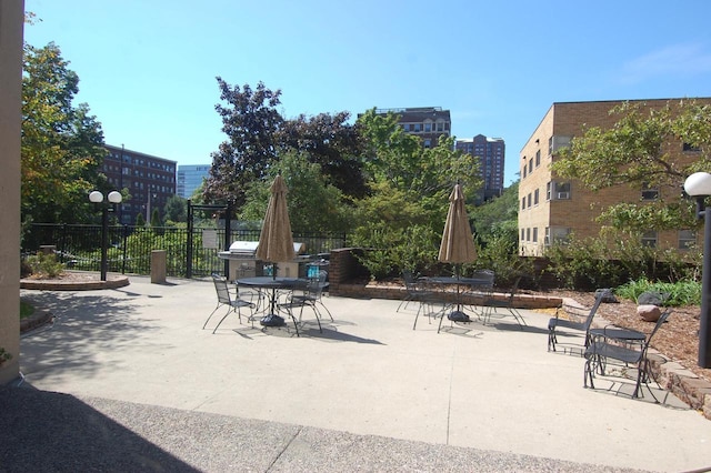 view of property's community with outdoor dining space, fence, a city view, and a patio