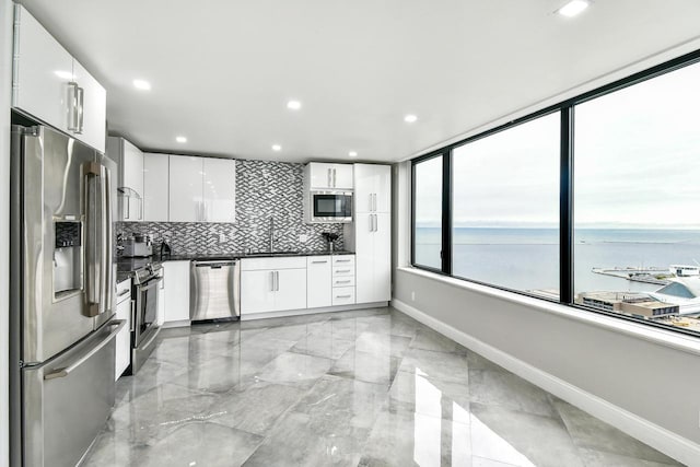 kitchen with a water view, white cabinetry, appliances with stainless steel finishes, tasteful backsplash, and dark countertops