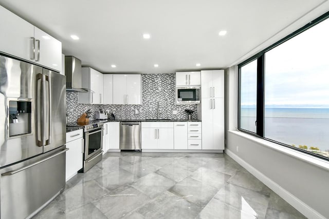 kitchen featuring white cabinets, dark countertops, a water view, stainless steel appliances, and wall chimney range hood