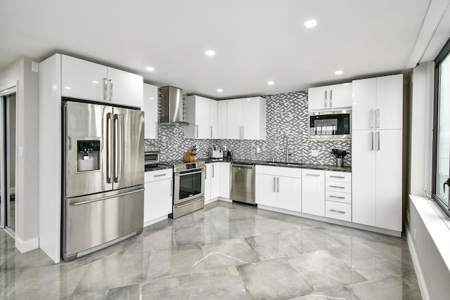 kitchen featuring appliances with stainless steel finishes, wall chimney range hood, and white cabinetry