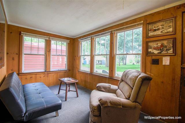 living area with wood walls, a healthy amount of sunlight, and carpet flooring