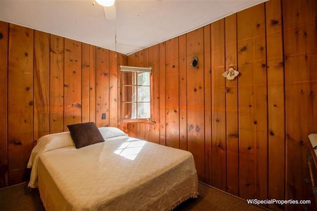 carpeted bedroom with ceiling fan and wood walls