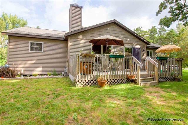 rear view of property with a wooden deck and a lawn