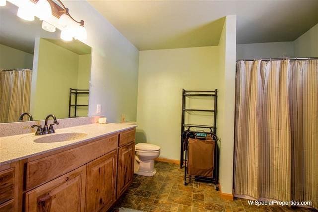 bathroom featuring toilet, tile floors, and vanity