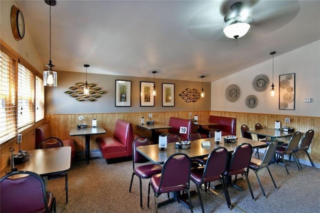 carpeted dining space with ceiling fan and vaulted ceiling