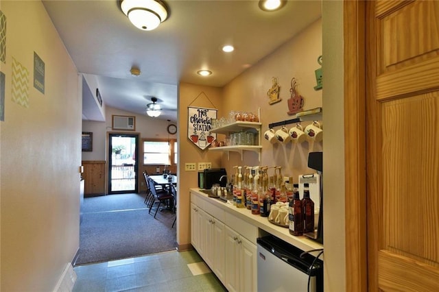 kitchen with white cabinetry, ceiling fan, dishwashing machine, light tile floors, and vaulted ceiling