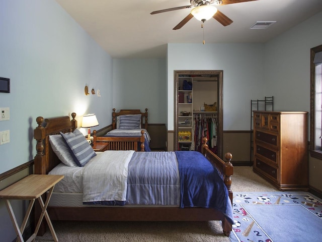 bedroom with ceiling fan, a spacious closet, dark carpet, and a closet