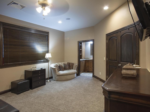 interior space featuring light carpet, connected bathroom, and ceiling fan