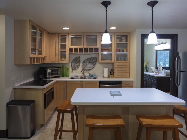 kitchen featuring pendant lighting, a kitchen bar, stainless steel fridge, dishwasher, and sink