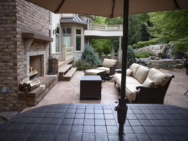 view of patio with a balcony and an outdoor living space with a fireplace