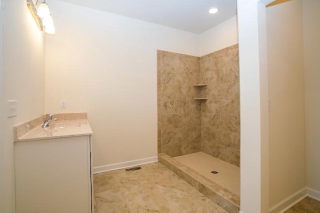 bathroom with tile flooring, a tile shower, and vanity