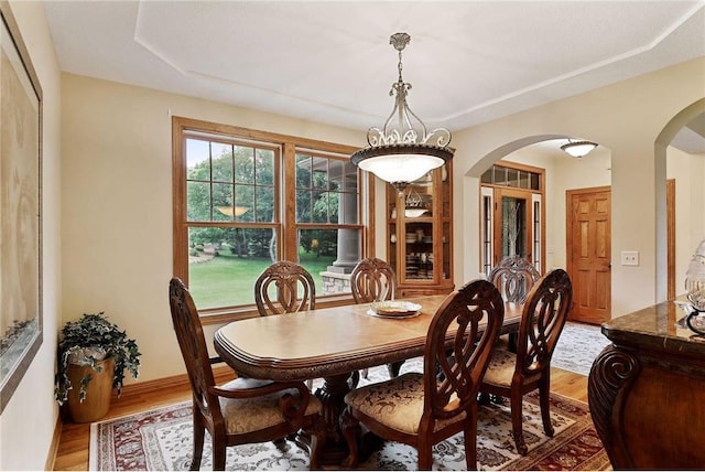 dining space with dark hardwood / wood-style flooring, a raised ceiling, and an inviting chandelier