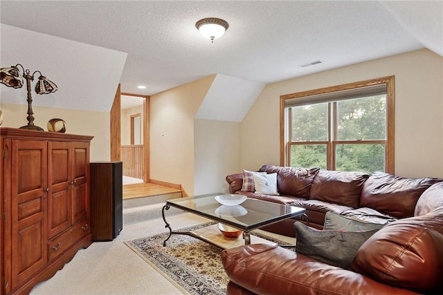 living room featuring lofted ceiling, a textured ceiling, and light colored carpet