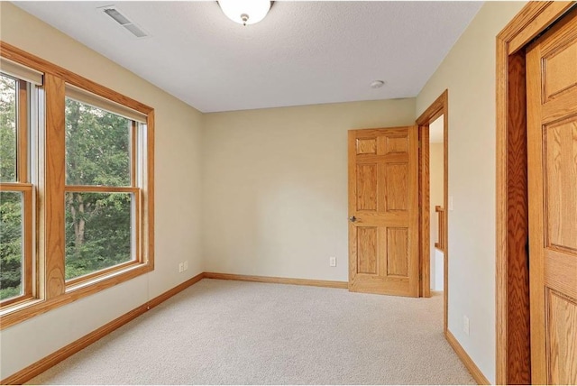 carpeted spare room featuring a wealth of natural light and a textured ceiling