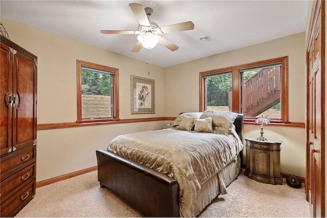 carpeted bedroom featuring a closet, multiple windows, and ceiling fan