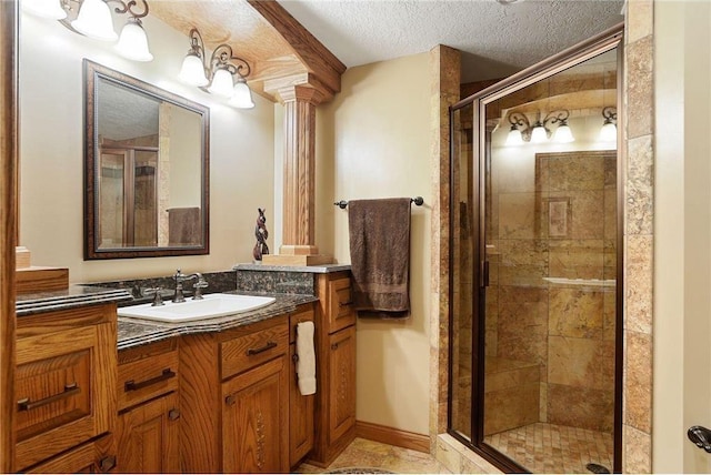 bathroom featuring vanity, a textured ceiling, a shower with door, and ornate columns