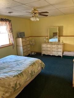 carpeted bedroom featuring ceiling fan and a paneled ceiling