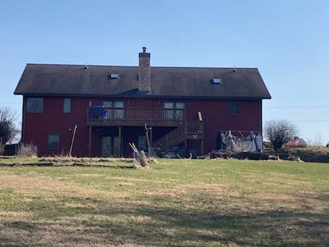 rear view of house featuring a deck and a yard