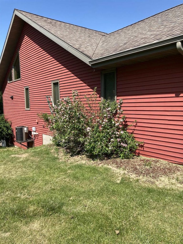 view of side of property featuring central AC unit and a yard