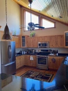 kitchen featuring appliances with stainless steel finishes, hanging light fixtures, hardwood / wood-style floors, ceiling fan, and high vaulted ceiling