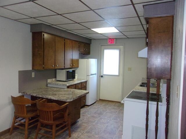 kitchen with extractor fan, light tile flooring, white fridge, and a paneled ceiling